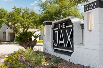 a white brick building with a black and white sign that reads the aax